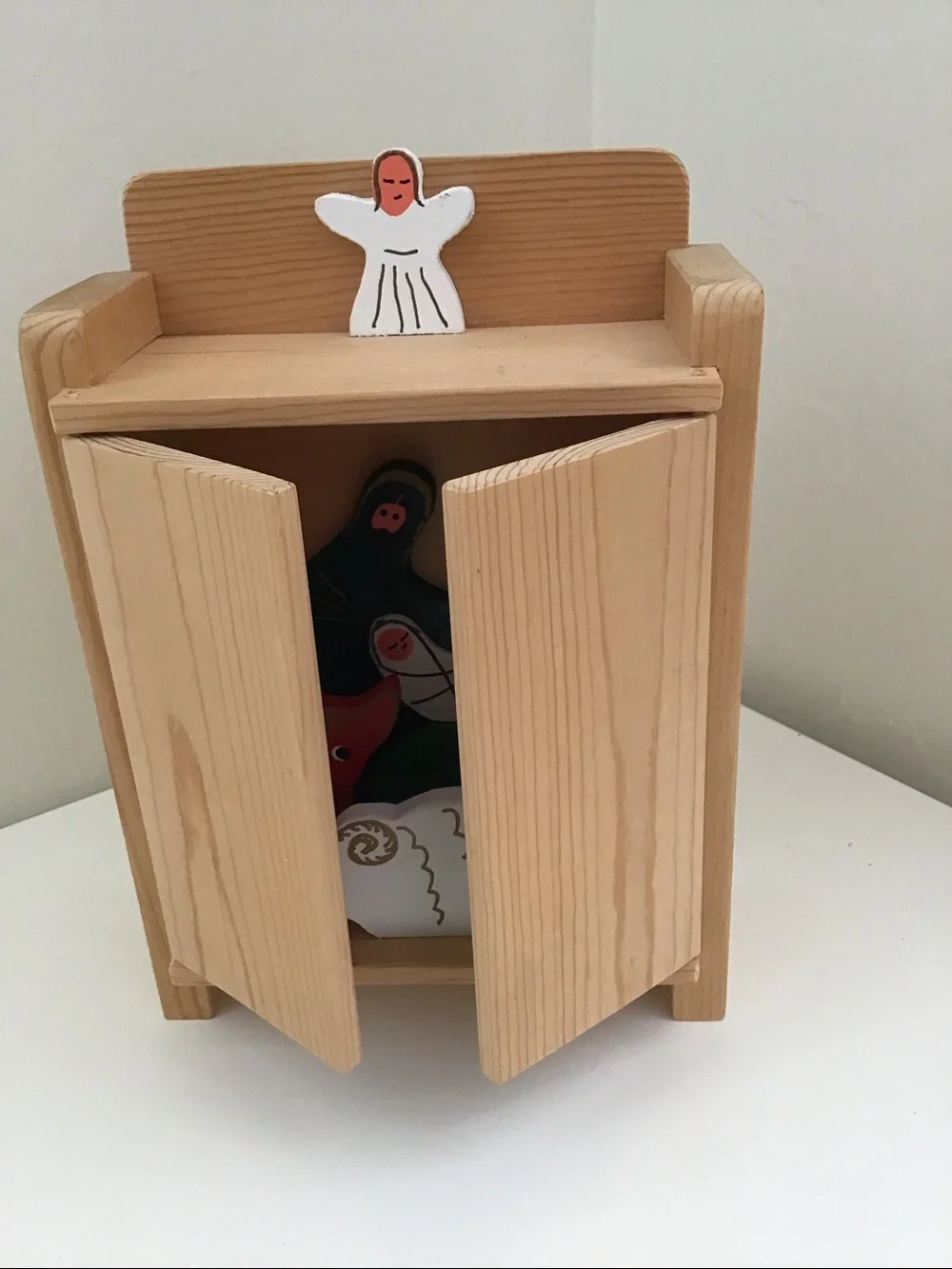 Handmade wooden cabinet holding a small wooden Nativity set